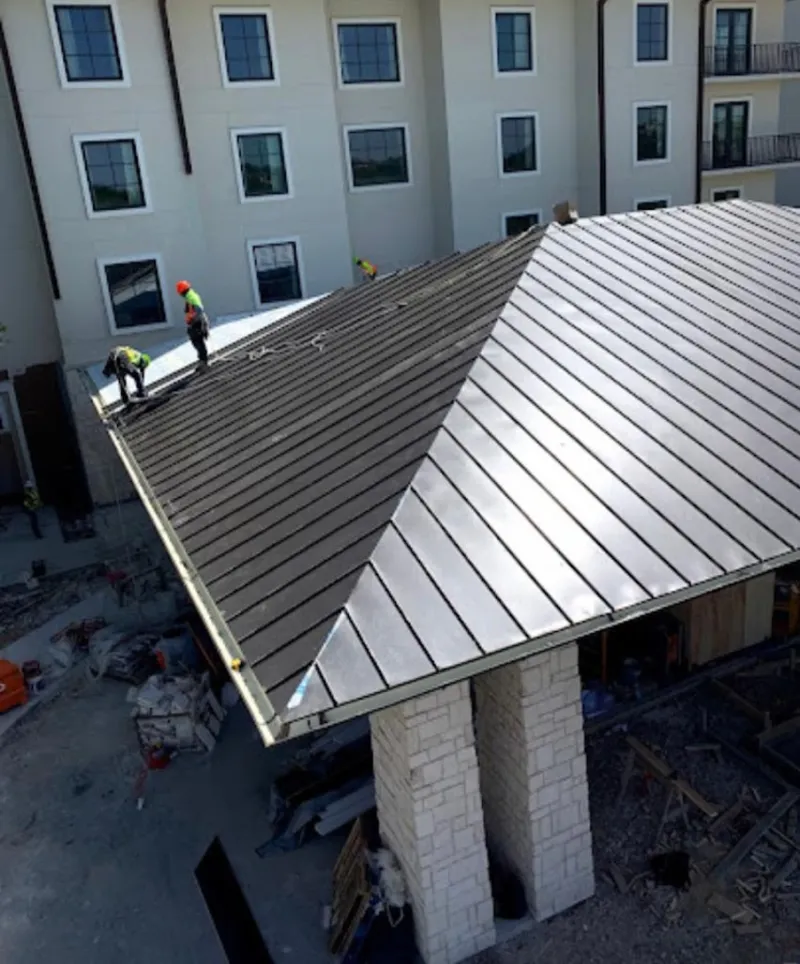 Crew installing standing seam metal roof panels on a commercial project in Carrollton